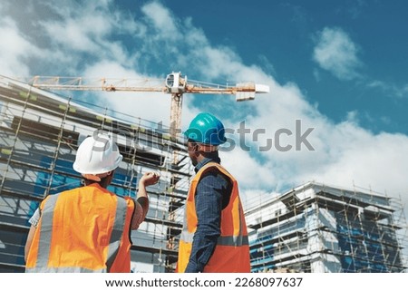 Their reputation is about to raise the roof. Shot of a young man and woman assessing progress of the building at a construction site.