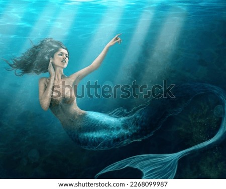 Siren of the sea. Shot of a mermaid swimming in solitude in the deep blue sea - ALL design on this image is created from scratch by Yuri Arcurs team of professionals for this particular photo shoot. Royalty-Free Stock Photo #2268099987