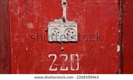 Electric socket ( 220V electricity ) on the red wall . The interior of an abandoned, dilapidated building. Devastated interior, torn out of the walls and cut electric cables .  