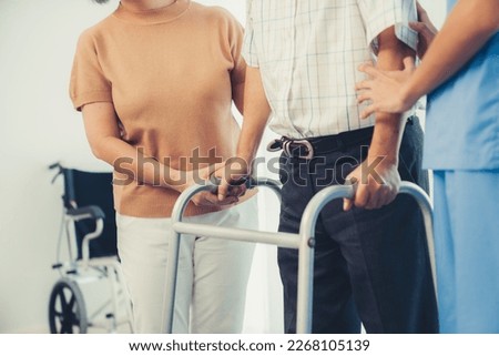 Contented senior man walking as he is helped by his wife and caretaker, walking with the aid of a folding walker. Nursing home for the elderly concept.