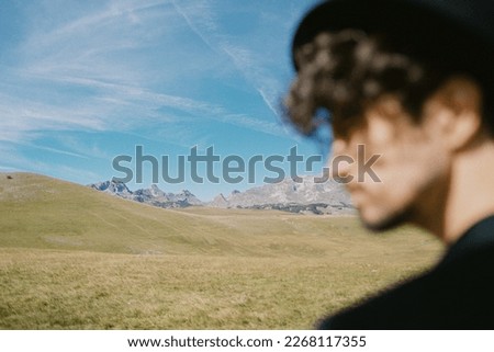 Profile of a young man in a hat against the backdrop of mountains and sky. Portrait