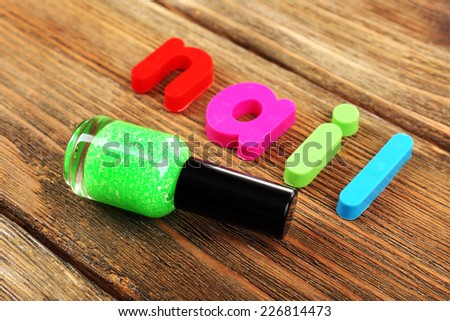 Nail word formed with colorful letters on wooden background