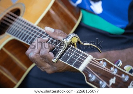 Mans hand is playing guitar, focus on fingers and mediator, close up
