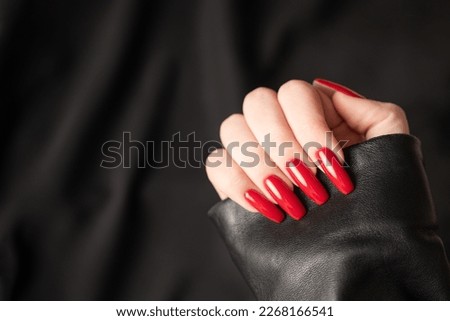 Hands of young girl with red  manicure on nails on black  background