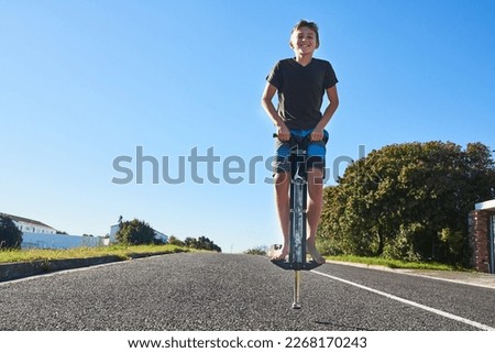 Lets bounce. Full length portrait of a young boy bouncing on a pogo stick outside. Royalty-Free Stock Photo #2268170243