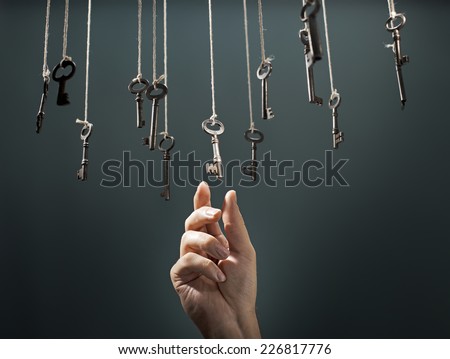 Hand choosing a hanging key amongst other ones. Royalty-Free Stock Photo #226817776