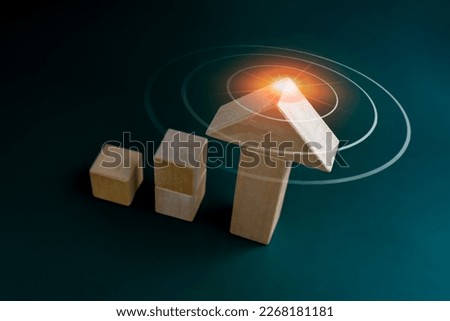 Target icon symbol on arrowhead wooden on cube blocks bar graph chart steps on dark blue background, top view. Investment, income, trends, inflation, business growth, economic improvement concepts.