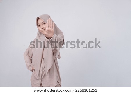 Portrait of asian girl wearing brown hijab doing stop sing with palm of the hand. warning expression with negative and serious gesture on the face. 