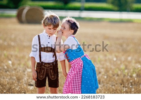 Two kids, boy and girl in traditional Bavarian costumes in wheat field with hay bales Royalty-Free Stock Photo #2268183723
