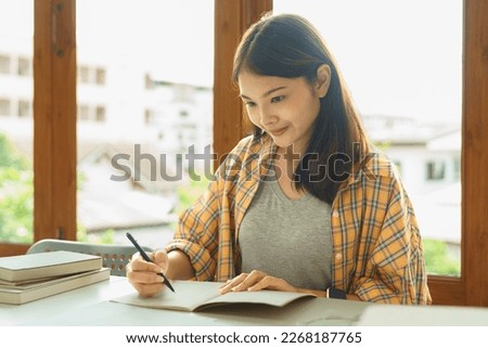 Education and literacy concept, College student girl read lesson sheet and take notes on notebook.
