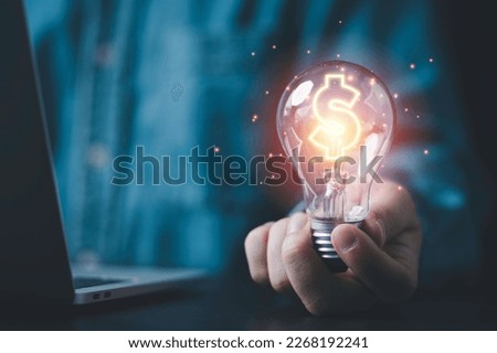 Businessman holding lightbulb and glowing dollar sign for creative thinking idea and problem solving can make more money concept. Royalty-Free Stock Photo #2268192241