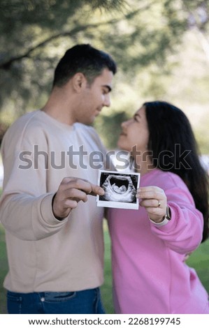 Pregnant couple holding ultrasound scan of their baby. Happy family pregnancy, expectation.