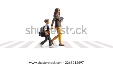 Full length profile shot of a woman carrying books and holding hands with a schoolboy on a pedestrian crossing isolated on white background Royalty-Free Stock Photo #2268212697