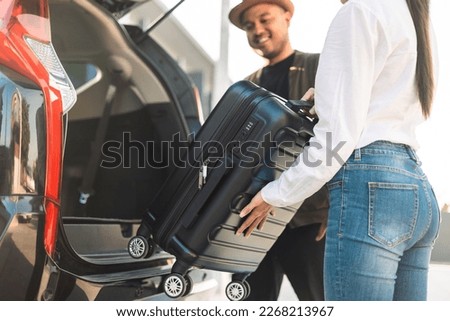 Happy couple puts his suitcase in the back of the car and prepares to leave for honeymoon trip. Husband and wife open the back of the car put luggage travel. Couple moving into new home at moving day Royalty-Free Stock Photo #2268213967