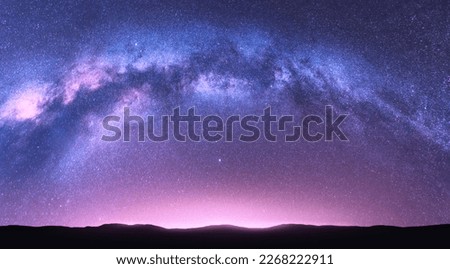Milky Way arch. Fantastic night landscape with bright arched milky way, purple sky with stars, pink light and hills. Beautiful scene with universe. Space background with starry sky. Galaxy and nature Royalty-Free Stock Photo #2268222911