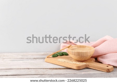 Board with bowl of tasty tahini, sesame seeds and spinach on light wooden table Royalty-Free Stock Photo #2268225025