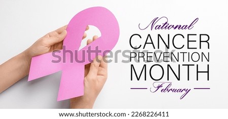 Banner with female hands holding paper awareness ribbon on white background. National Cancer Prevention Month Royalty-Free Stock Photo #2268226411
