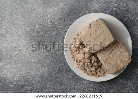 Compressed yeast on grey table, top view. Space for text