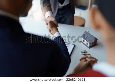 Asian real estate agent shaking hands handing over house and keys to his client's house after client sign contract