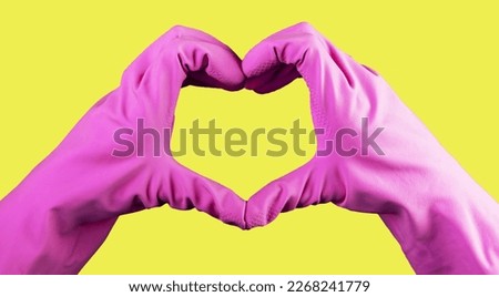Heart-shaped sign, gesture with hand in violet gloves of cleaner, cleaning service with love concept, yellow background.