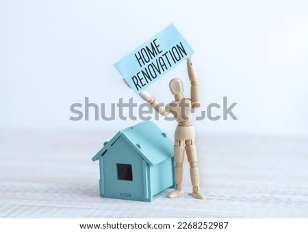 Home Renovation text on paper in the hands of a wooden man and wooden home.