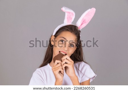 Sweet little girl wearing bunny ears eating chocolate Easter egg. Easter in Brazil