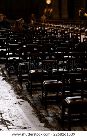 Rows of chairs in dark half-empty Catholic church.