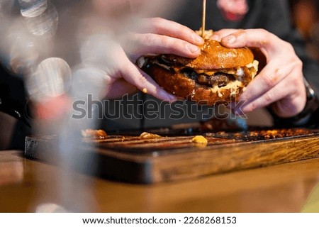 man hands hold fast food burger in pub