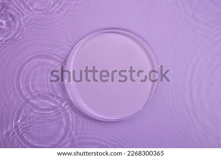 Top view of transparent round empty podium, splashes and bubbles on the purple surface water background. Empty platform for cosmetics. Blank minimal design concept.