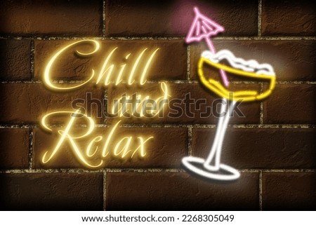 Glowing neon sign with cocktail glass and phrase Chill And Relax on brick wall