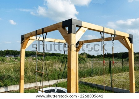 A modern cubic playground made of wooden logs and metal corners, visible nylon ropes and clip hook. Royalty-Free Stock Photo #2268305641