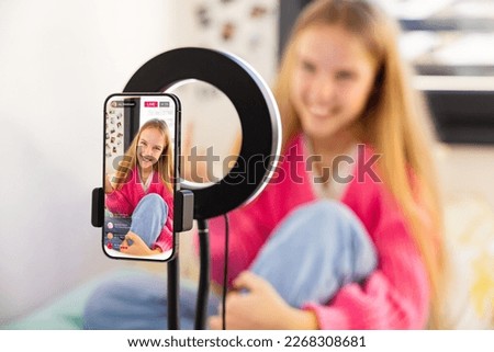 Teenage girl filming herself with mobile phone at home and live streaming on social media Royalty-Free Stock Photo #2268308681