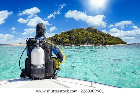 A scuba diver in his diving gear sits in front of a boat and enjoys the view of the tropical landscape with turquoise sea in Krabi, Thailand Royalty-Free Stock Photo #2268309901