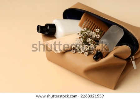 Preparation for spa. Compact toiletry bag with different cosmetic products and flowers on beige background, closeup. Space for text Royalty-Free Stock Photo #2268321559