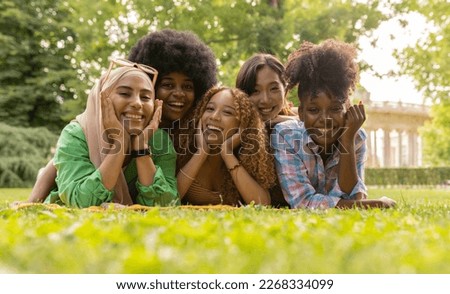 group pretty multiracial women on the grass on a picnic, day lying down looking at camera
