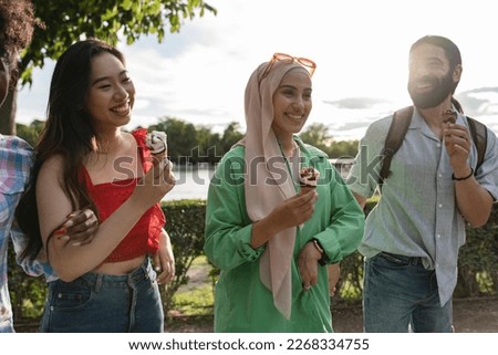 diverse female friends eating ice cream in the park - focus on arab woman - Royalty-Free Stock Photo #2268334755