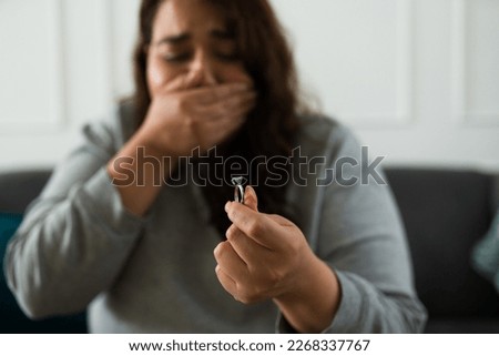 Sad young woman crying looking at her engagement ring while feeling depressed about her heartbroken breakup from her ex-fiance