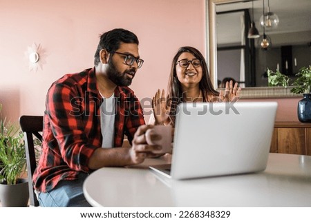 Latino or indian man and woman couple use their laptop in the living room to make video calls. Video call and online chat with family