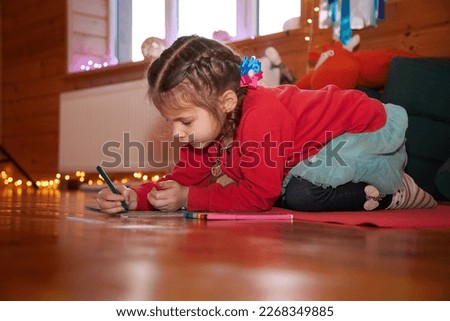 Close up view of a small kid drawing a picture on the floor while mother doing yoga.