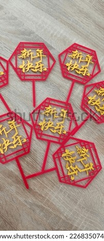 Cakes Topper on the wooden table. Gold color is chinese letters. Those Chinese letters meaning is happy new year. 