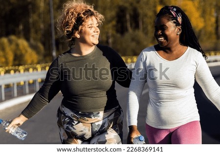 Two young plus size women jogging together. Royalty-Free Stock Photo #2268369141