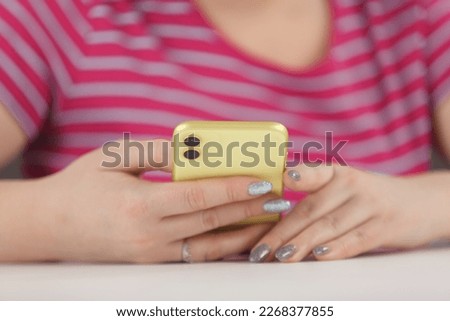 Young girl browsing mobile app on yellow smart phone with dual camera. Close up photo of a female person using modern mobile phone 