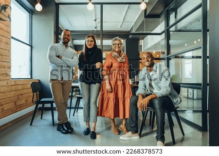 Team of successful businesspeople smiling at the camera in an office boardroom. Group of multicultural businesspeople working together in a modern workplace. Royalty-Free Stock Photo #2268378573
