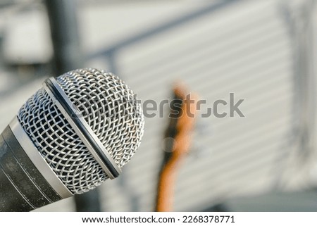 close-up dynamic microphone with an acoustic guitar on the blurred background outdoors, copy space, music and entertainment concept.
