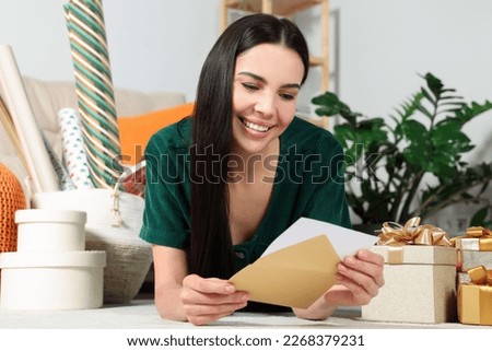 Happy woman reading greeting card on floor in living room