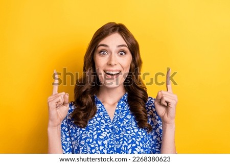 Photo of young overjoyed funny girl manager wear blue shirt direct fingers up good salary new vacancy proposition isolated on yellow color background