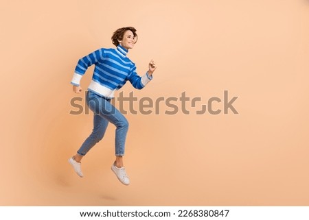 Full body length photo of active running hurry woman fast speed motivation career empty space blue striped sweater isolated on beige color background