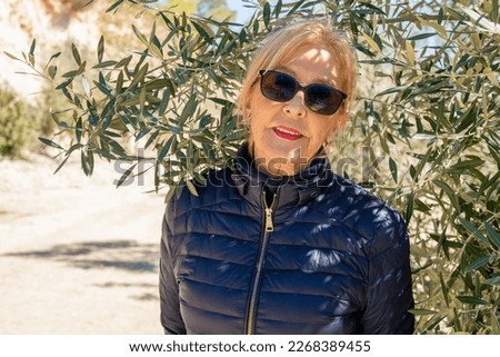 Portrait of smiling senior woman relaxing in a park. A photo on the nature background