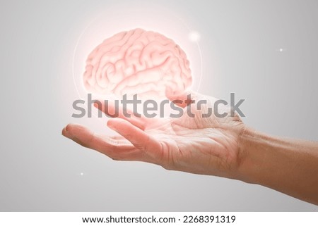 Man holding brain illustration against gray wall background. Concept with mental health protection and care. Royalty-Free Stock Photo #2268391319