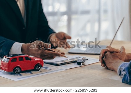 Salesman offers prices and interest rates on car sales with insurance in the office at the desk.
